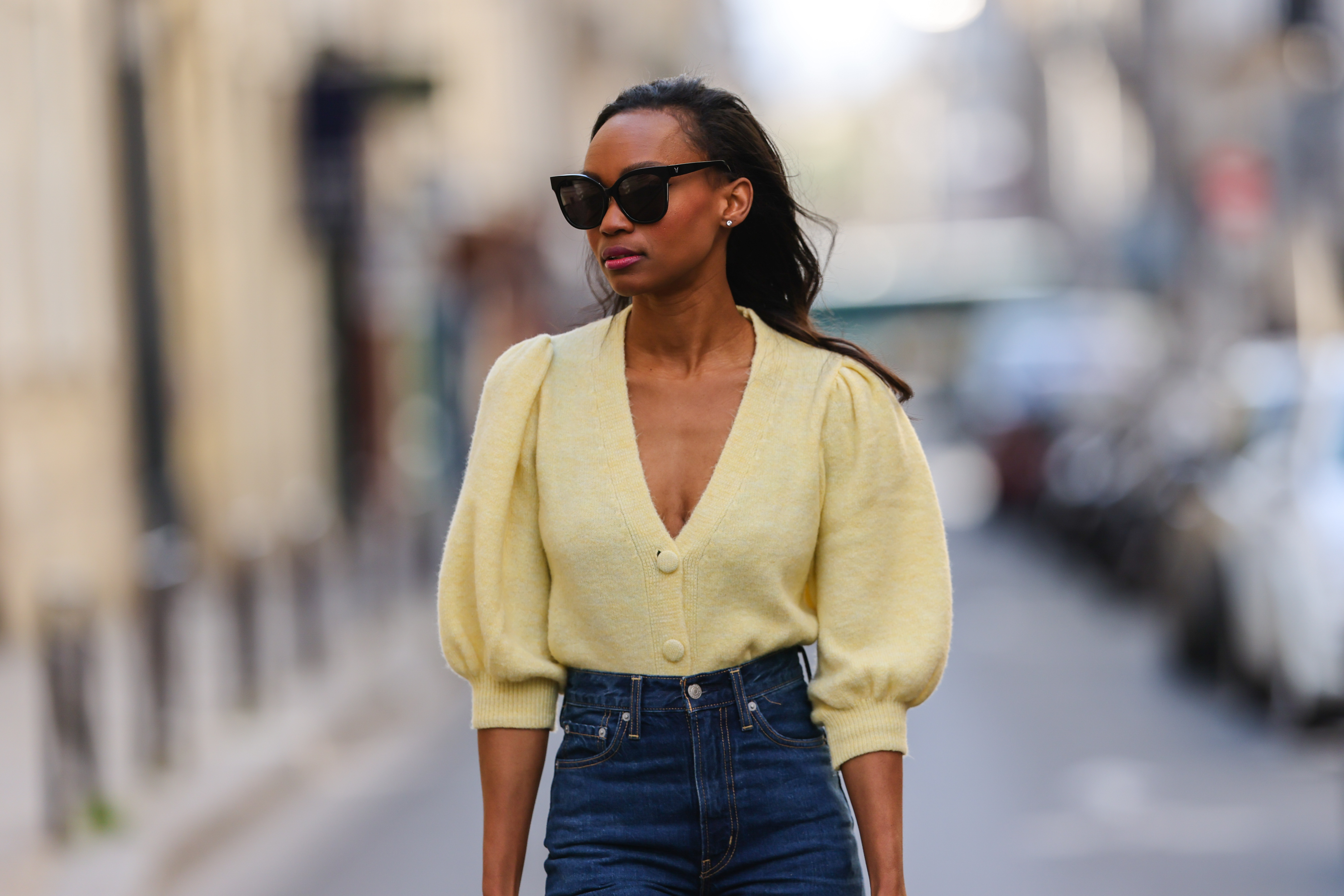 PARIS, FRANCE - APRIL 03: Emilie Joseph @in_fashionwetrust wears sunglasses, pale pastel yellow a puffed sleeves wool cardigan from Mango, high rise blue denim jeans pants from Levi's, on April 03, 2021 in Paris, France. (Photo by Edward Berthelot/Getty Images)