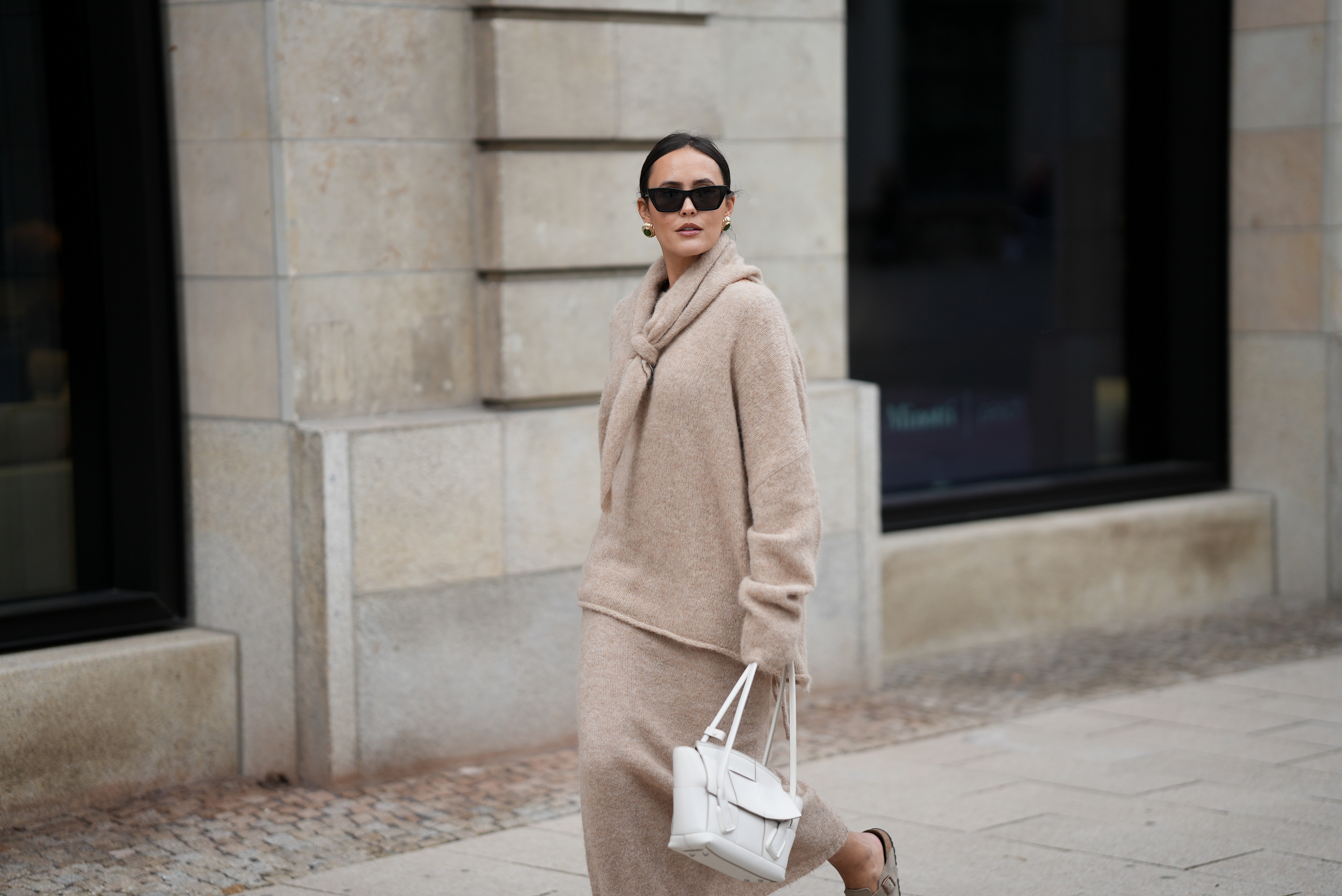 Laura Noltemeyer is seen wearing an oversized beige alpaca wool sweater with tie-back detailing by Aylin König; a long alpaca wool knit skirt in a straight cut by Aylin König; an alpaca knit scarf draped and knotted around the neck by Aylin König; a white intrecciato leather handbag called „Arco Bag“ by Bottega Veneta; slim black cat-eye sunglasses by Yves Saint Laurent; gold statement earrings with a green stone detail by Mango; her brown and straight hair is tied in a low ponytail on October 16, 2025 in Hamburg, Germany.