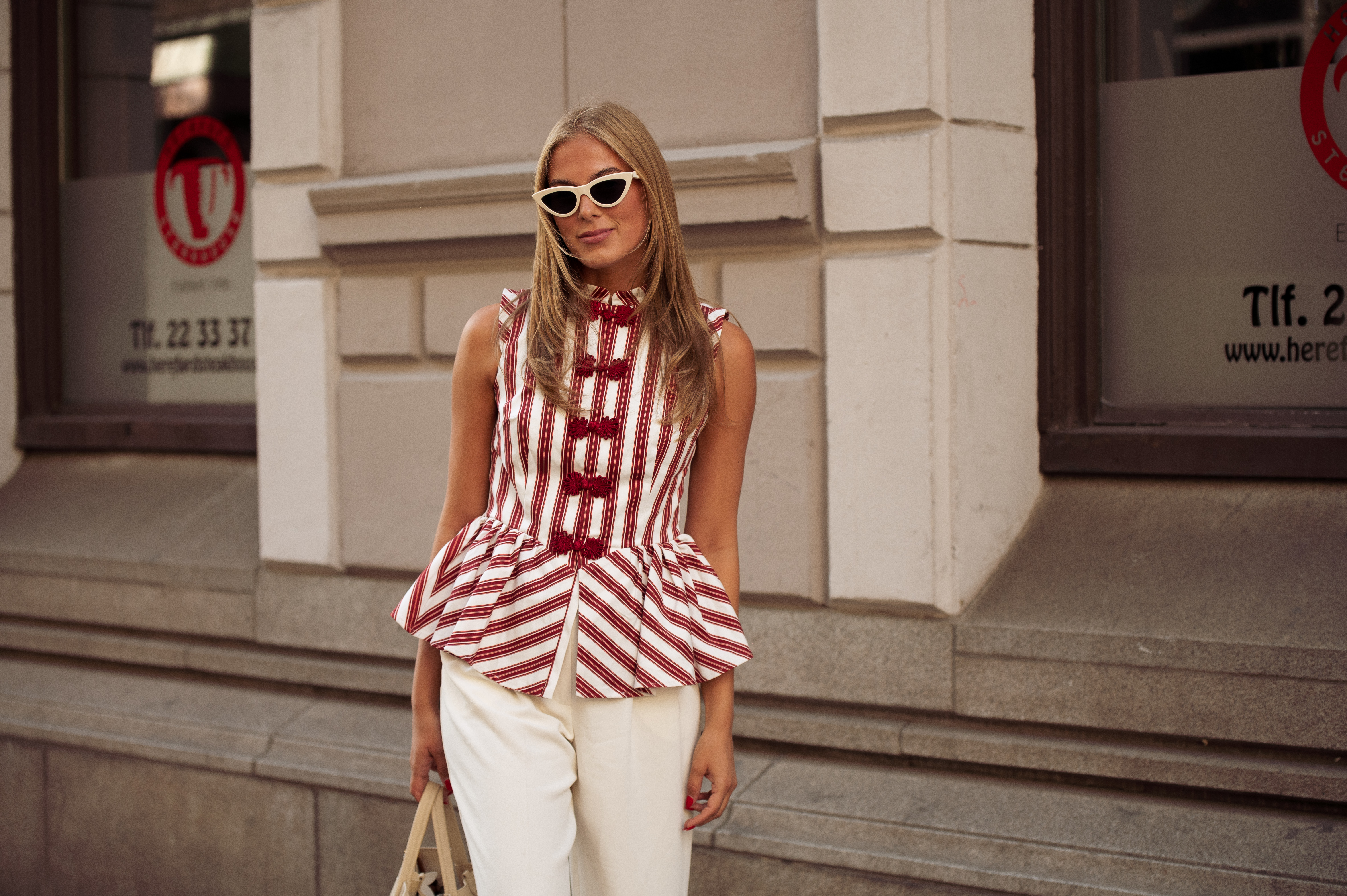 Martine Akersveen wears white pants, red and white striped top and a beige bag outside the Christian Aks show during Oslo Fashion Week on August 26, 2025 in Oslo, Norway.
