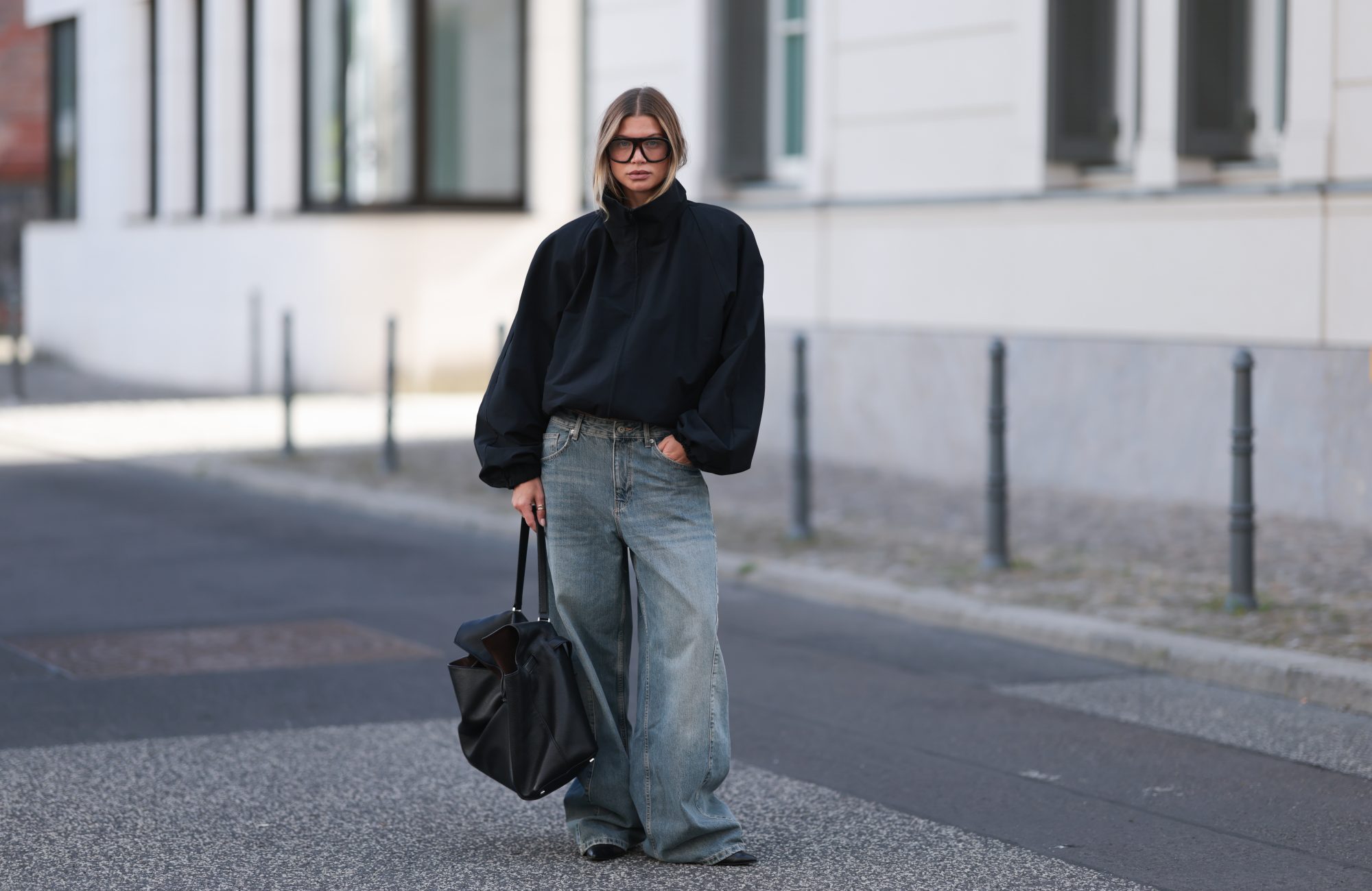 BERLIN, GERMANY - SEPTEMBER 23: Sophia Geiss seen wearing Prada oversized black aviator shades, Zara black oversized high-neck jacket layered over a black top, The Frankie Shop faded blue wide-leg jeans, COS oversized black leather tote bag, Calvin Klein black pointed-toe shoes on September 23, 2026 in Berlin, Germany. (Photo by Jeremy Moeller/Getty Images)